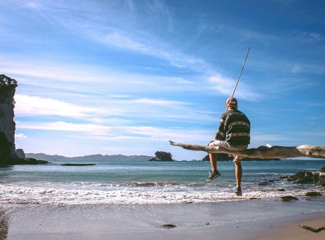 person sitting on driftwood near seashore during daytime